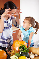 Image showing Playful, pumpkin for halloween and a mother with her daughter in the kitchen of their home together for holiday celebration. Smile, happy or funny face with a woman and girl child carving a vegetable