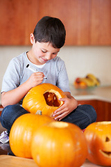 Image showing Halloween, pumpkin and boy child in the kitchen for holiday celebration at modern home. Creative, smile and happy young kid bonding and carving vegetable for decoration or tradition at family house.