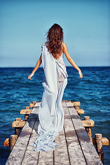 Image showing Woman, elegant and promenade with dress by beach, confident and fashion clothes for trendy designer collection. Model, usa and luxury in chiffon gown for fancy, blue and natural for style by ocean