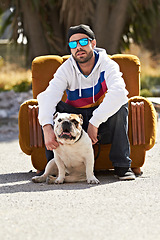 Image showing Couch, city and portrait of man with dog in street for urban fashion, casual style and trendy outfit. sunglasses, pets and person on sofa in road with canine, bulldog and best friend for relaxing