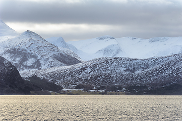 Image showing Snow-Covered Mountain Range Overlooking the Calm Sea Under Cloud