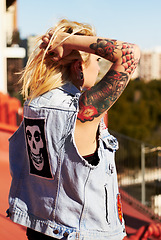 Image showing Back, tattoo and a woman tying her hair outdoor in the city for travel, freedom or adventure on vacation. Fashion, style and a funky young punk rocker person looking at a view overseas or abroad