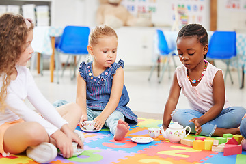 Image showing Kids, tea party and playing for fun in school with friends, together and bonding. Diversity, little girls and face with toy on mat for child development, motor skills and growth for future in daycare