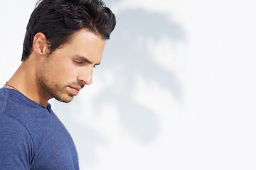 Image showing Thinking, sad and man profile by a white wall outdoor in the sun with freedom and ideas. Relax, peace and male person with mockup and summer with vitamin D, leaning and contemplating with outfit