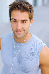 Image showing Fitness, portrait and man athlete running with sweat on road for exercise, cardio or outdoor training. Active, sports and young male person with smile and earphones for music, playlist or album.