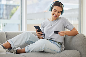 Image showing Sofa, headphones and phone with credit card and woman at home with purchase, music and smile. Online shopping, tech and internet with banking and audio with mobile by a sofa with digital buying