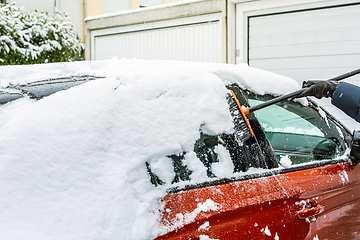 Image showing Cleaning snow from windshield. Cleaning and clearing the car from snow on a winter day. 