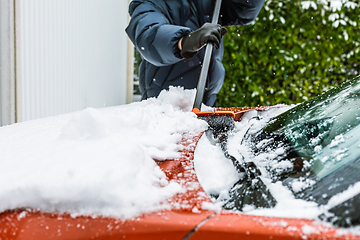 Image showing Cleaning snow from windshield. Cleaning and clearing the car from snow on a winter day. 