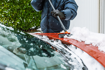 Image showing Cleaning snow from windshield. Cleaning and clearing the car from snow on a winter day. 