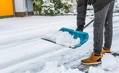 Image showing Cleaning snow from street in winter with shovel after snowstorm. Cleaning sidewalk from snow on a winter day. 