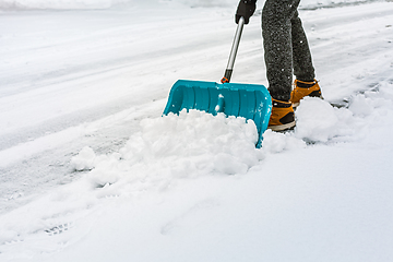 Image showing Cleaning snow from street in winter with shovel after snowstorm. Cleaning sidewalk from snow on a winter day. 