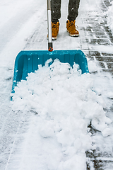 Image showing Cleaning snow from street in winter with shovel after snowstorm. Cleaning sidewalk from snow on a winter day. 