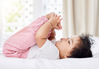 Image showing Baby, feet and hands with curiosity in bedroom for motor skills, growth or development. Little girl, toddler and grab of toes, looking and playing with excitement, discovery and milestone in home