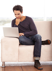 Image showing Man, work from home and thinking on computer for stock market investment, reading information or website on sofa. Freelancer or trader on his laptop with trading software, choice or online decision