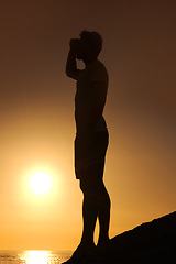Image showing Silhouette, man or looking with hands for view, scenery and wellness on beach with sunset and peace. Person, shadow or adventure and relax for holiday, vacation or experience by ocean or sea with sun