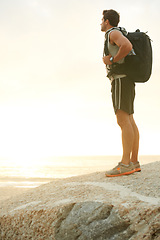 Image showing Man, backpack or rock and cliff in nature for travel, adventure or scenery with sunshine, thinking or view. Person, mountain or sky for holiday, vacation or experience outdoor and freedom or trekking