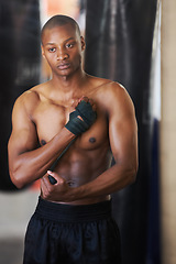 Image showing Boxing, gym and black man wrapping hands with fitness, power and training challenge. Strong body, muscle workout and boxer in gym, athlete with confidence and getting ready for fighting competition.