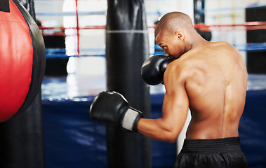 Image showing Black man, boxer and punching bag at gym for workout, exercise or self defense practice in fighting sport. African male person with boxing gloves for indoor training or martial arts at health club