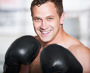 Image showing Boxing, gloves and portrait of happy man with fitness, power and training for challenge in gym. Strong body, muscle and smile, boxer or athlete with fist up, face and confidence in competition fight.