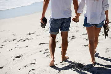 Image showing Love, holding hands and couple walking on beach for date, outdoor bonding and tropical holiday. Romance, man and woman from back, legs and relax on vacation together with travel, care and adventure.