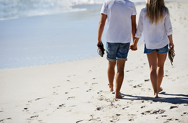 Image showing Legs, holding hands and couple walking on beach for date, outdoor bonding and tropical holiday. Romance, man and woman from back, love and relax on vacation together with travel, care and adventure.