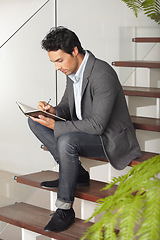 Image showing Businessman, writing and sitting on stairs for journal, planning or reminder in living room at home. Man, freelancer or employee working or taking notes in book or diary for business plan or proposal