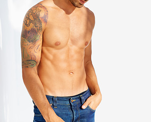 Image showing Fashion, tattoo and shirtless with a man outdoor on a white background for edgy or unique style. Health, fitness and denim jeans with the body of a model in the sunlight for masculine or macho style