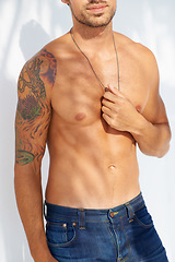 Image showing Health, tattoo and body with a man outdoor on a white background for edgy or unique style. Fashion, fitness and denim jeans with a shirtless model in the sunlight for masculine or macho style