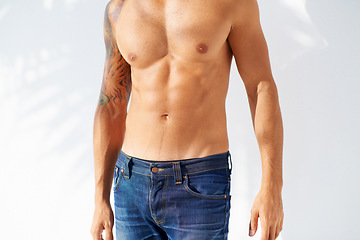 Image showing Fashion, tattoo and body with a man outdoor on a white background for edgy or unique style. Health, fitness and denim jeans with a shirtless model in the sunlight for masculine or macho style
