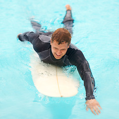 Image showing Man, surfing and happy in water, sports and exercise on vacation, holiday and adventure in ocean. Male person, athlete and smile for hobby, paddle and freedom in nature, active and fitness on board