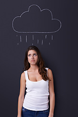 Image showing Thinking, sad and rain cloud with woman on a chalkboard for drawing, emotion or expression in studio. Depression, idea or weather and an unhappy young person with a chalk picture of a winter storm