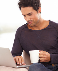 Image showing Coffee, laptop and online with man on sofa for social media, networking and connection. Website, streaming and digital with person in living room at home for remote work, research and technology