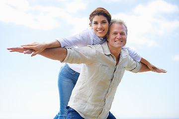 Image showing Mature couple, portrait and piggy back on vacation, airplane hands and happiness in blue skies. Man, woman and bonding together with smile, marriage and commitment with affection, holiday and joyful