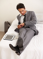 Image showing Businessman, watch and checking time on bed at hotel for schedule, reservation or reminder at house. Man or employee looking at wristwatch for monitoring stay, deadline or accommodation in bedroom