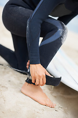 Image showing Foot, ankle and strap with a surfer on the beach closeup, getting ready for sports or fitness training. Hands, hobby and tie with a person on the sand at the coast for safety during an exercise hobby