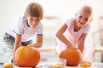 Image showing Halloween, portrait and carving a pumpkin with children at a home table for fun and bonding. Boy and girl or young kids as siblings together for creativity, holiday lantern and happy craft and play