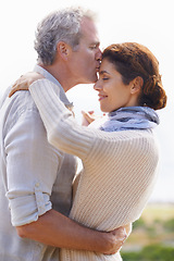 Image showing Couple, kiss and hug in outdoors, travel and bonding or love, affection and security in relationship. Mature people, happy and relaxing on vacation, holiday and adventure or getaway, embrace or care