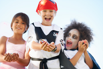 Image showing Children, halloween and costume or hands for candy asking as dracula dress up, fairy or pirate role play. Friends, group and happy for sweet dessert or celebration for fantasy, fun on sky background