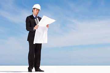 Image showing Industry, blueprint and man engineer by blue sky on building rooftop for planning for maintenance. Career, mockup space and professional male industrial worker with architecture drawing for project.