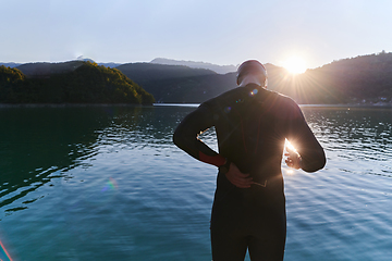 Image showing Authentic triathlon athlete getting ready for swimming training on lake