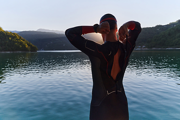 Image showing Authentic triathlon athlete getting ready for swimming training on lake