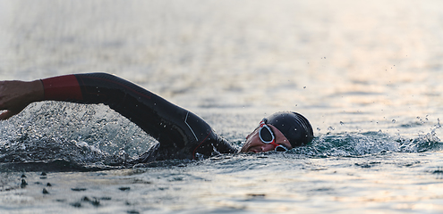 Image showing A professional triathlete trains with unwavering dedication for an upcoming competition at a lake, emanating a sense of athleticism and profound commitment to excellence.