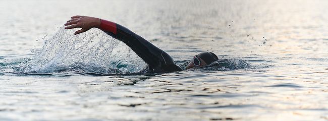 Image showing A professional triathlete trains with unwavering dedication for an upcoming competition at a lake, emanating a sense of athleticism and profound commitment to excellence.