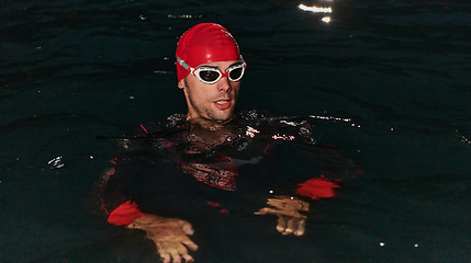 Image showing A determined professional triathlete undergoes rigorous night time training in cold waters, showcasing dedication and resilience in preparation for an upcoming triathlon swim competition