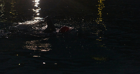 Image showing A determined professional triathlete undergoes rigorous night time training in cold waters, showcasing dedication and resilience in preparation for an upcoming triathlon swim competition