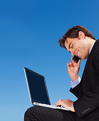 Image showing Laptop, phone call and happy business man in conversation, listening or communication on blue sky mockup space. Computer, mobile chat and lawyer networking, discussion or legal advice on smartphone