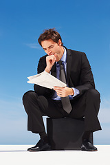 Image showing Yawn, newspaper and businessman reading information sitting by the outdoor blue sky with burn out. Tired, exhausted and sleepy professional young male person in a suit sitting with magazine report.