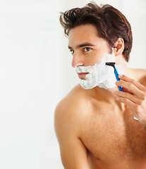 Image showing Skincare, shaving and razor with a man in the bathroom of his home for grooming or morning routine. Face, beauty and foam with a young person in his apartment to shave his beard for hair removal