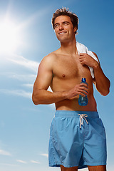 Image showing Man, shirtless and water bottle or towel for workout with health body, fitness or happiness on vacation. Model, smile or natural glow with drink for hydration or post exercise in sunshine with shorts