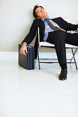 Image showing Business man, sleeping and case in lobby, chair and fatigue from travel, overworked or burnout in suit. Entrepreneur, briefcase and tired with rest, exhausted or luggage for corporate job with stress